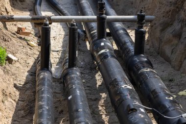 Büyük siyah boruları olan yeraltı siperleri modern su tedarik sistemi için monte edilip tamir ediliyor. Kentsel altyapı, inşaat süreci, kamu hizmetleri bakımı ve kamu hizmeti geliştirme