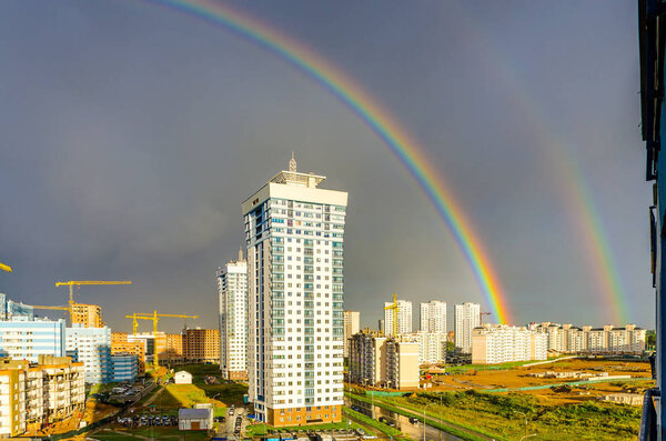 Colorful rainbow stretching over high-rise buildings of city
