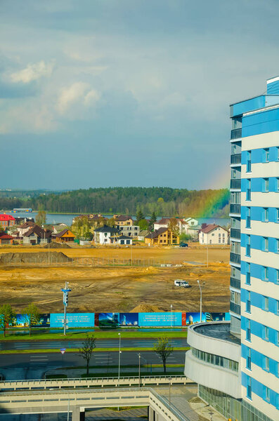 Colorful rainbow stretching over high-rise buildings of city