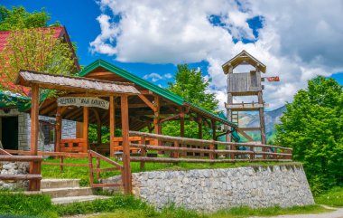 MONTENEGRO, MOUNTAINS PROKLETIJE - MAY 29, 2017: Tourists visited restaurant located on plain between high snow-capped mountains clipart
