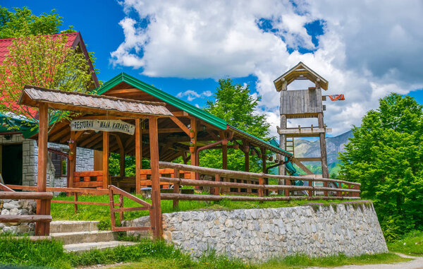 MONTENEGRO, MOUNTAINS PROKLETIJE - MAY 29, 2017: Tourists visited restaurant located on plain between high snow-capped mountains