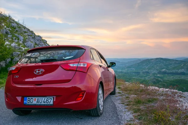 stock image MONTENEGRO - MAY 31, 2017: red car parked by tourists on roadside of serpentine for sightseeing