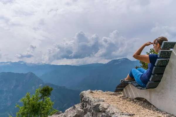 Young woman resting on bench on top of mountain with panoramic view