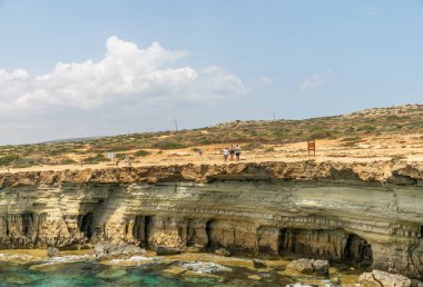 Kıbrıs, Aya Napa - 11 Mayıs 2008: Turistler pitoresk deniz mağaraları yakınında sahil boyunca yürüyüş.