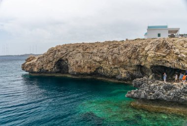 Kıbrıs - 11 Mayıs 2018: Turistler merdivenlerden Akdeniz kıyısındaki bir mağaraya indiler.