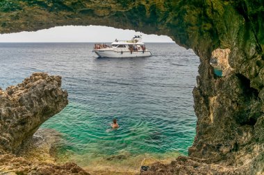 Kıbrıs - 11 Mayıs 2018: Turistler Akdeniz kıyısındaki bir mağaraya gezi teknesiyle gittiler.