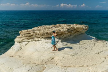 Genç ve güzel bir kadın deniz arka planında poz veriyor.