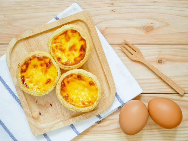 Fresh baked egg tarts or custard tarts (pastel de nata) on wooden plate