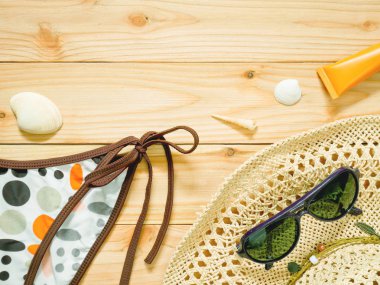 Bikini altları, güneş gözlüğü, plaj şapka ve güneş koruyucu kopya alanı ile ahşap arka plan üzerinde. Bayan beachwear aksesuarlar deri ve gözleri güneşten korumak için. Yaz tatil kavramı.