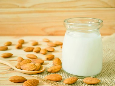 Bir kavanoz ile ahşap masa üzerinde kabuklu badem badem sütü