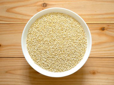 Bir kase çiğ beyaz Quinoa ahşap masa üzerinde. Üstten görünüm.