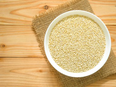 Bir kase çiğ beyaz Quinoa kopya alanı ile ahşap masa üzerinde. Üstten görünüm. 