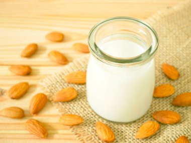 Bir kavanoz ile ahşap masa üzerinde kabuklu badem badem sütü