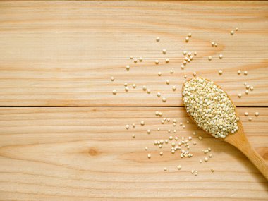 Tahta kaşıkla kopya alanı içinde pişmemiş beyaz quinoa yığını. Üstten görünüm.