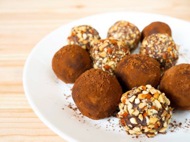 Ev yapımı koyu çikolata truffles ve kavrulmuş badem çikolatalar beyaz plaka üzerinde
