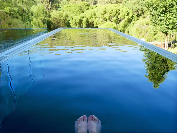 Woman\'s feet on swimming pool in the garden