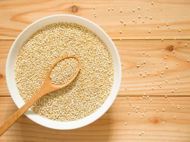Bir kase çiğ beyaz Quinoa ahşap masa üzerinde. Üstten görünüm.