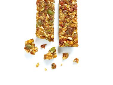 Kepekli tahıl çubukları veya kabak çekirdeği ile kek ve beyaz arka plan üzerinde izole kırıntıları ile kurutulmuş meyve. Üstten görünüm.