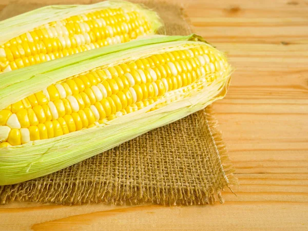 Ears of bicolor sweet corn on rustic wooden background with copy space