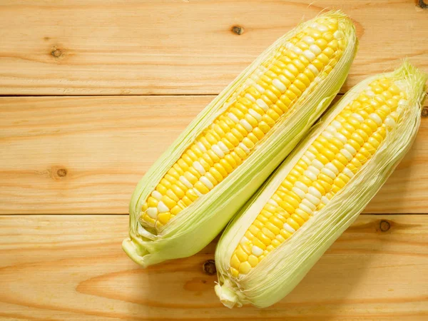 Ears of bicolor sweet corn on rustic wooden background with copy space. Top view.