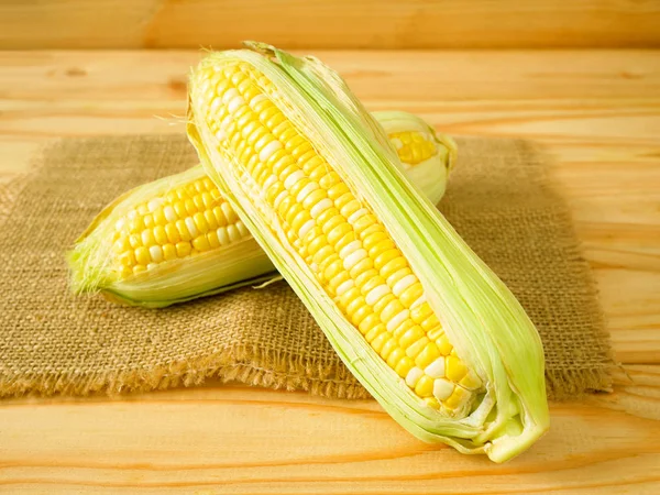 Ears of bicolor sweet corn on rustic wooden background