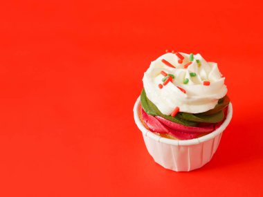 Noel kek krem peynir frosting ve kırmızı bir arka plan üzerinde renkli şeker strand sprinkles ile