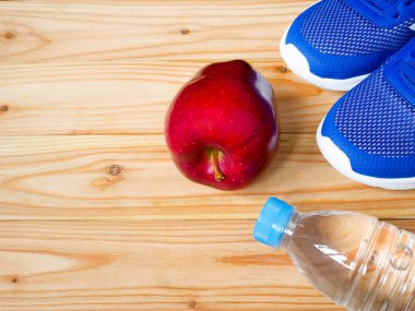 Egzersiz ve fitness ekipmanları ile kopya alanı ile spor salonunda ahşap arka plan üzerinde kırmızı elma. Üstten görünüm. Sağlık kavramı