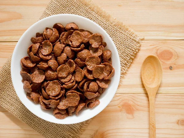 木製テーブルの上の白いボウルにコーンフレークをチョコレート 平面図です 健康的な朝食のコンセプト — ストック写真