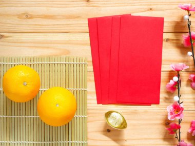 Çin yeni yıl süslemeleri. Kırmızı paketleri, portakal, altın külçe ve erik çiçeği. Üstten görünüm.