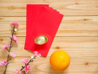 Çin yeni yıl süslemeleri. Kırmızı paketleri, portakal, altın külçe ve erik çiçeği. Üstten görünüm. Kopya alanı.