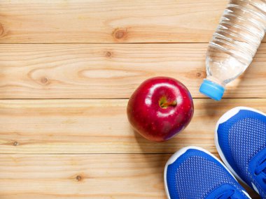 Egzersiz ve fitness ekipmanları ile kopya alanı ile spor salonunda ahşap arka plan üzerinde kırmızı elma. Üstten görünüm. Sağlık kavramı