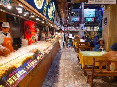 Lijiang, Çin - 22 Nisan 2019: Aşçılar hazırlamak, yemek ve Lijiang eski kasabasında gıda mahkemesinde kendi gıda satın almak için müşterileri ikna