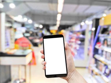 Süpermarketin arka planında cep telefonu boş duruyor.