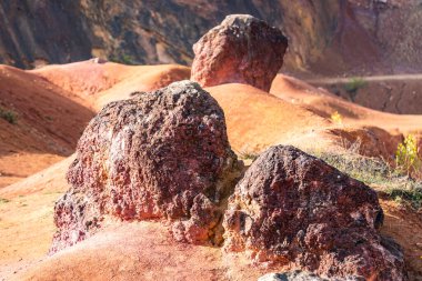Terk edilmiş bir boksit madeninde parlak turuncu renklerle erozyona uğramış bir kayalık oluşumu.