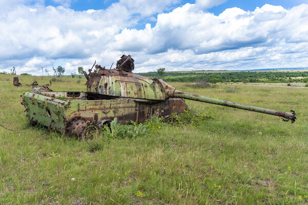Старый уничтоженный русский танк Т-54 на травянистом поле