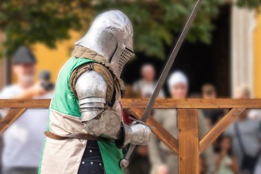 Medieval knight with longsword in armor at a jousting tournament