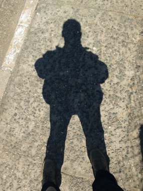 Güneşli bir günde ayakta duran adamın gölgesi.