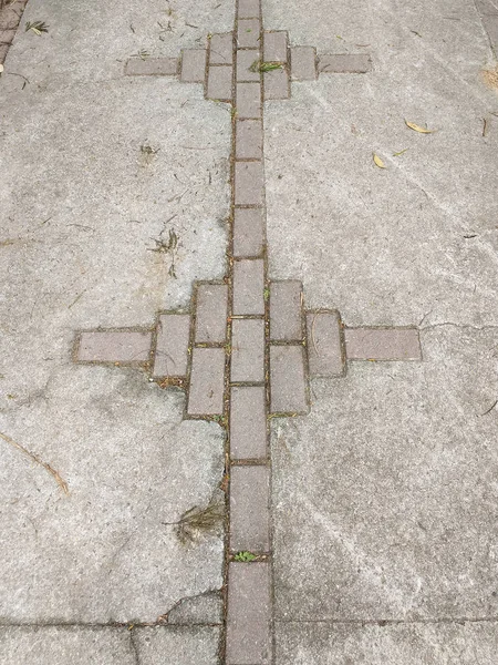 Rustic cement sidewalk with cracks and bricks in perspective.