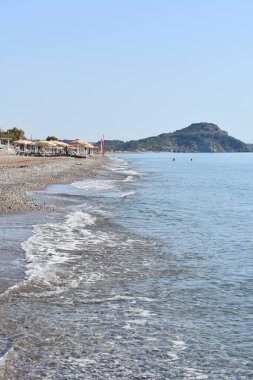 Akdeniz 'deki Afandou köyü yakınlarındaki çakıl ve kumsal, Rodos Adası, Yunanistan. Dağ manzaralı deniz manzaralı. Yunanistan 'da turizm ve plaj tatilleri. Temiz su ve çakıl taşı plajı. Yunanistan 'a Seyahat. 