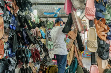 Markette çeşitli sandalet ve terlikleri karıştıran biri..