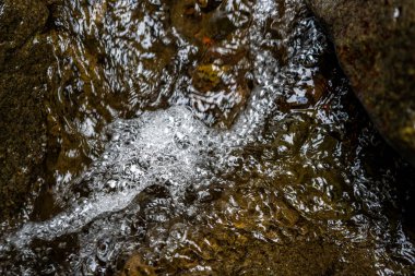 Kayaların üzerinden akan kaynayan suyun yakın çekimi..