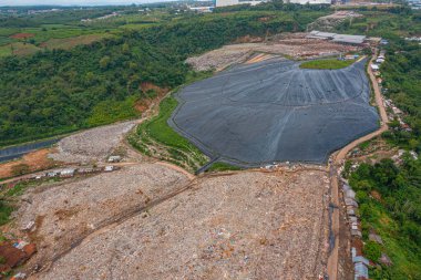 Atık ve kaplanmış kısımlarla dolu büyük bir çöp sahasının havadan görünümü.