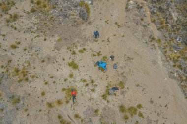 Kayalık bir arazide seyrek bitki örtüsü olan yürüyüşçülerin hava manzarası