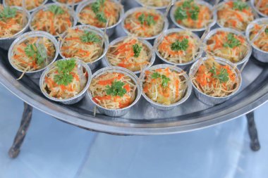 Bir tepsi dolusu renkli otlarla süslenmiş yemek.