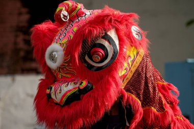 Karmaşık desenleri ve dokuları olan canlı bir kırmızı aslan dans kostüm başlığı geleneksel kültür unsurlarını sergiliyor.
