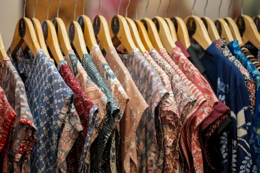 Ahşap askılarda asılı renkli desenli gömlekler var.