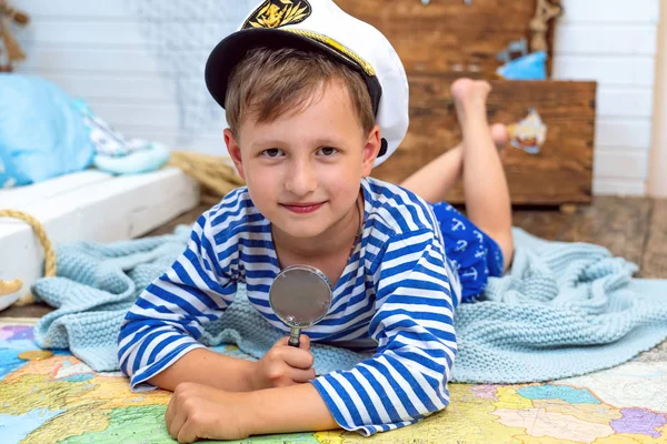 小男孩在一个水手在他的房间里玩耍的形象 通过放大镜卡进行检查 — 图库照片