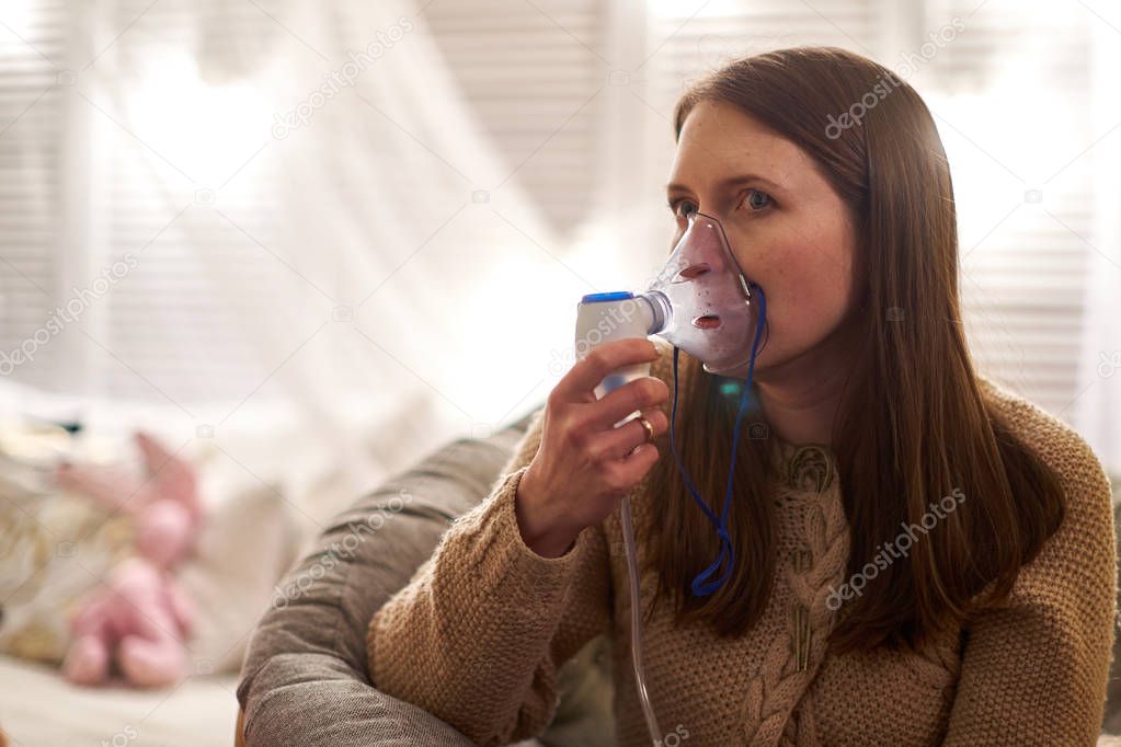 woman makes inhalation nebulizer at home. holding a mask nebulizer inhaling fumes spray the medication into your lungs sick patient. self-treatment of the respiratory tract using inhalation nebulizer