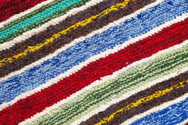 farklı renkli çizgili örme kumaş yüzeyinde. Tekstil retro close-up arka plan halı veya kilim. kumaş dokusuna satırların geometrisi ile bir kombinasyonudur. El yapımı ürün