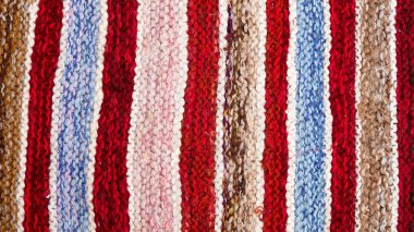 farklı renkli çizgili örme kumaş yüzeyinde. Tekstil retro close-up arka plan halı veya kilim. kumaş dokusuna satırların geometrisi ile bir kombinasyonudur. El yapımı ürün